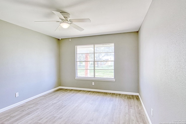 spare room featuring wood finished floors, a ceiling fan, and baseboards