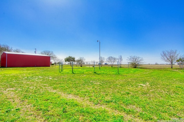 view of yard featuring a rural view, a pole building, fence, and an outdoor structure