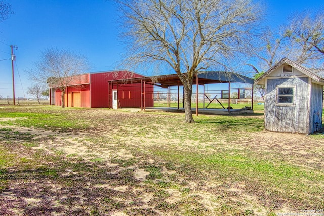 view of yard with an outbuilding, fence, a garage, a pole building, and driveway