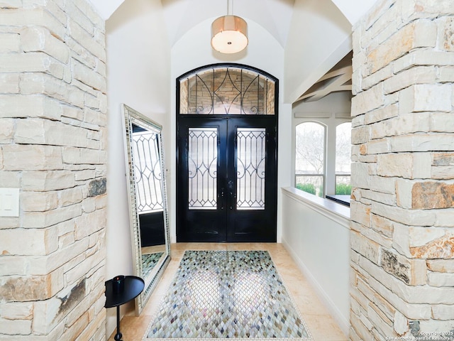 foyer with french doors, light tile patterned flooring, and a high ceiling