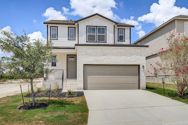 view of front of house featuring stone siding, a front lawn, board and batten siding, and concrete driveway