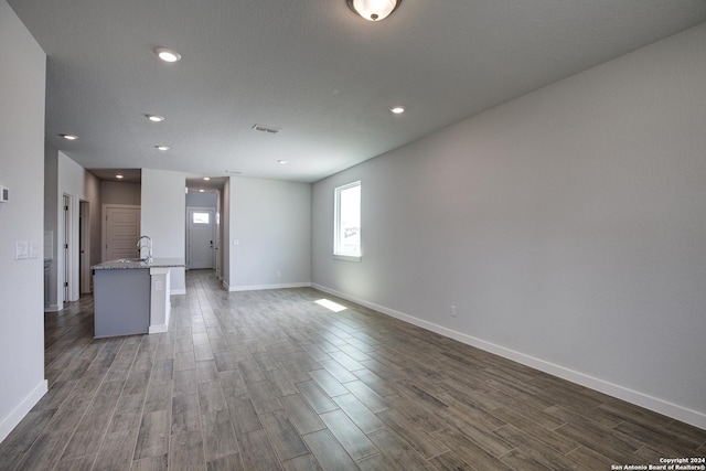 unfurnished living room with dark wood-style flooring, recessed lighting, visible vents, and baseboards