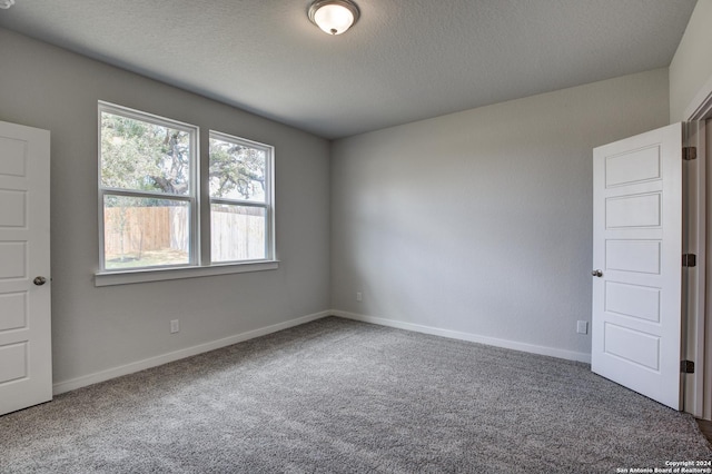 carpeted spare room with a textured ceiling and baseboards