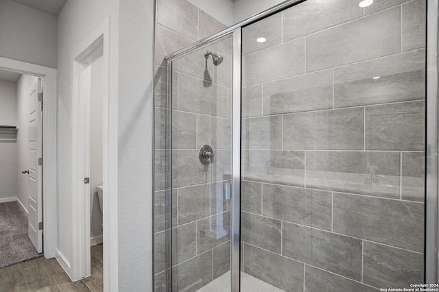 bathroom with a shower stall and wood finished floors