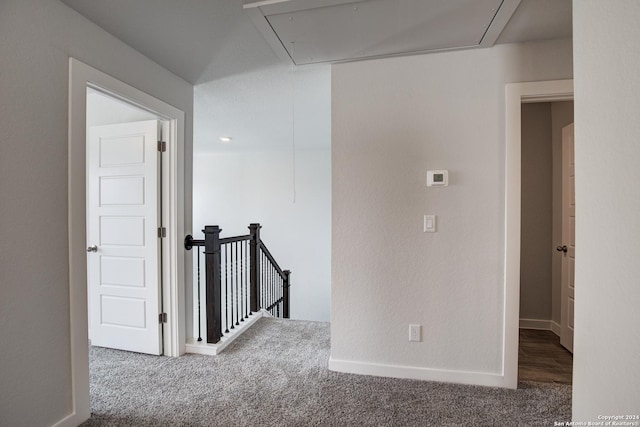 hall with carpet, an upstairs landing, attic access, and baseboards