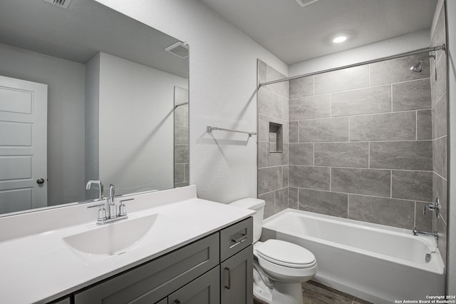 bathroom with toilet, wood finished floors, visible vents, vanity, and washtub / shower combination