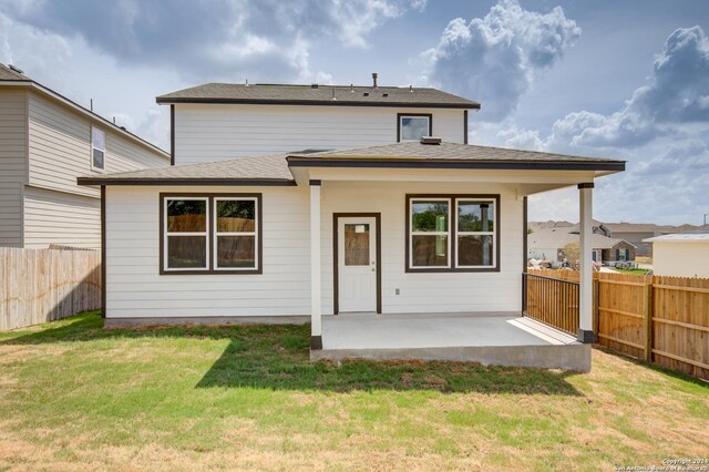 rear view of house featuring a fenced backyard, a shingled roof, a lawn, and a patio