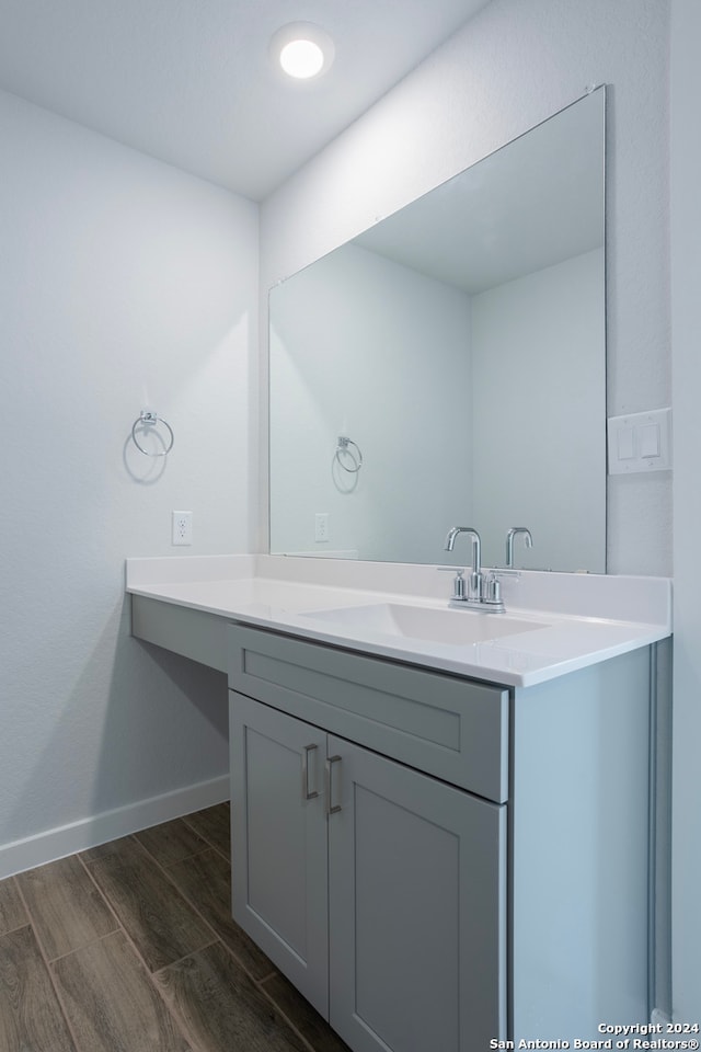 bathroom with wood finish floors, vanity, and baseboards