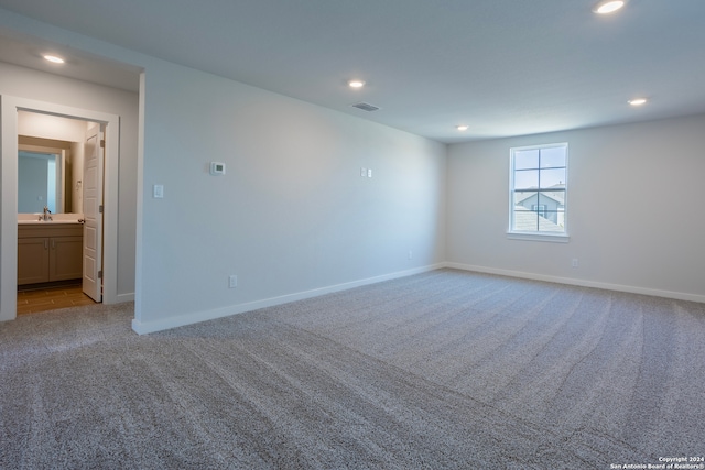 spare room with carpet, a sink, visible vents, and recessed lighting