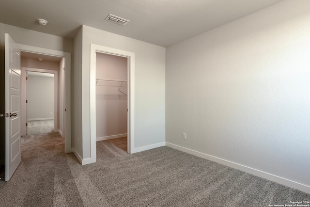 unfurnished bedroom with carpet flooring, visible vents, baseboards, a spacious closet, and a closet