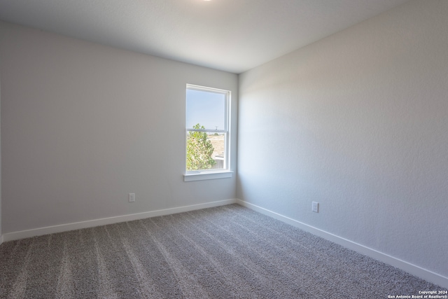 carpeted empty room featuring baseboards