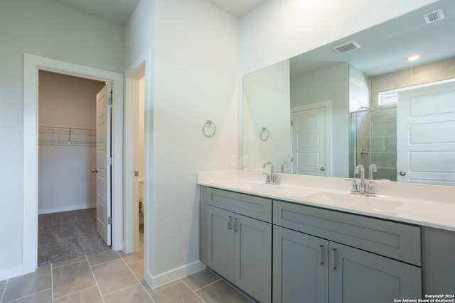 bathroom with double vanity, a stall shower, tile patterned flooring, and a sink