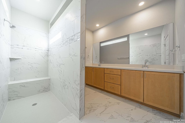 bathroom with marble finish floor, double vanity, recessed lighting, a tile shower, and a sink