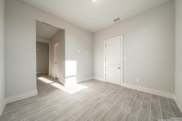 spare room featuring baseboards, visible vents, and wood finish floors