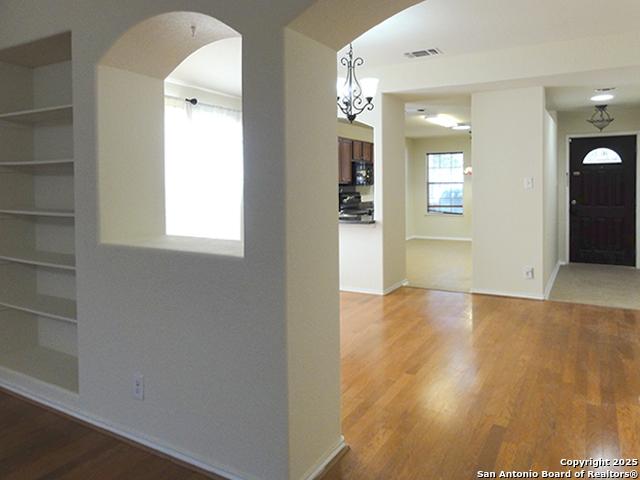 entryway featuring baseboards, visible vents, arched walkways, and wood finished floors