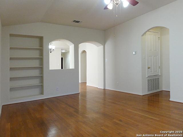 unfurnished room featuring lofted ceiling, wood finished floors, a ceiling fan, and built in features