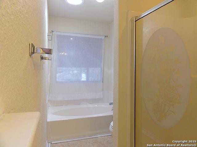 bathroom with a tub to relax in, a textured wall, toilet, a shower with door, and tile patterned flooring