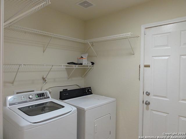 washroom with laundry area, visible vents, and washer and dryer