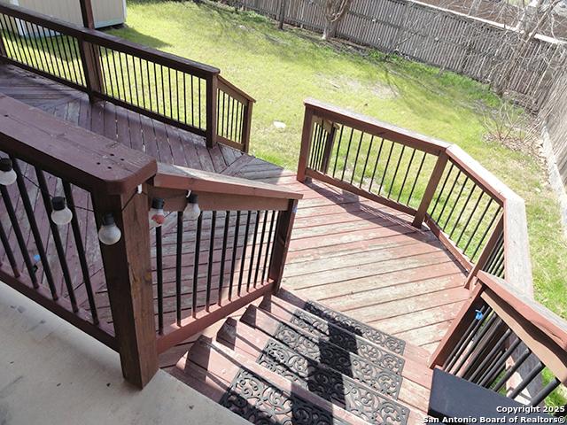 wooden terrace featuring fence and a yard