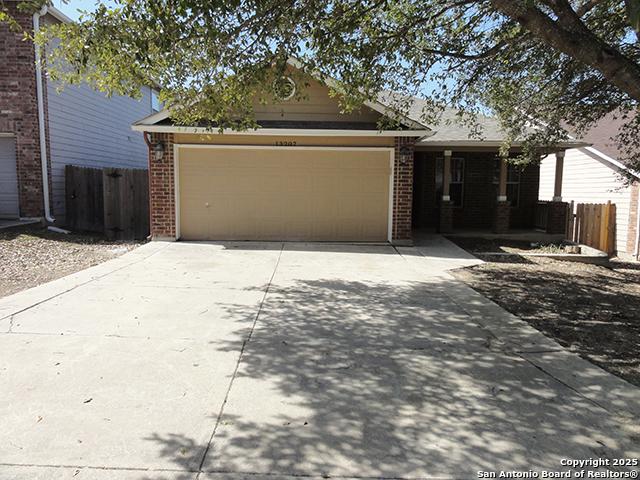 ranch-style house with an attached garage, fence, concrete driveway, and brick siding