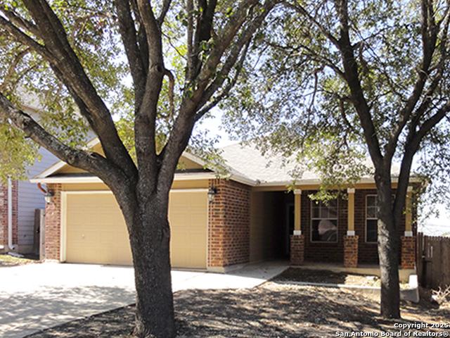 ranch-style home featuring a garage, driveway, fence, and brick siding