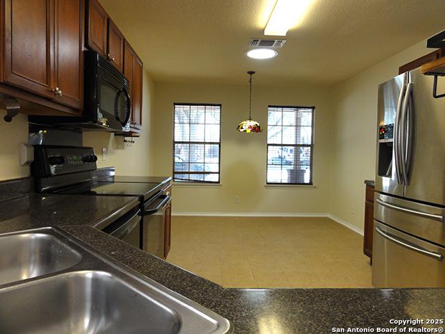 kitchen with dark countertops, black appliances, visible vents, and decorative light fixtures