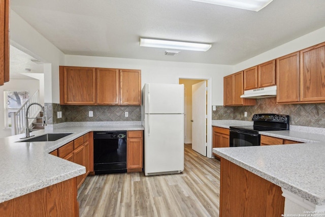 kitchen featuring a peninsula, under cabinet range hood, light countertops, black appliances, and a sink