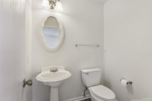 half bathroom featuring baseboards and toilet