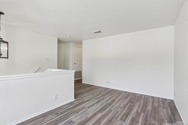 unfurnished room featuring visible vents, baseboards, and wood finished floors