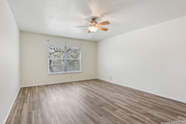 spare room with ceiling fan, a textured ceiling, baseboards, and wood finished floors