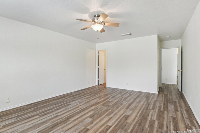 unfurnished room with visible vents, ceiling fan, a textured ceiling, wood finished floors, and baseboards