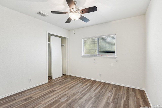 unfurnished bedroom with wood finished floors, visible vents, a ceiling fan, baseboards, and a closet