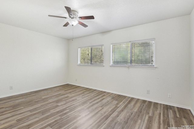 spare room featuring ceiling fan, wood finished floors, and baseboards