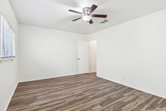 empty room with a ceiling fan, visible vents, baseboards, and wood finished floors