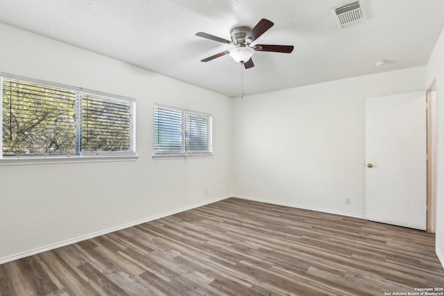 unfurnished room with baseboards, ceiling fan, visible vents, and wood finished floors