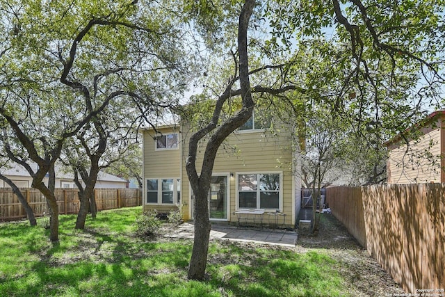 rear view of property with a fenced backyard, a lawn, and a patio