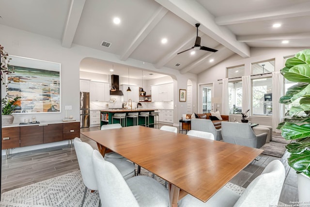 dining space featuring arched walkways, recessed lighting, lofted ceiling with beams, wood tiled floor, and ceiling fan