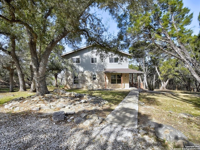 view of front of house featuring covered porch, brick siding, and a front lawn