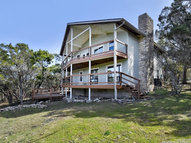 rear view of property featuring a yard, a chimney, a wooden deck, and a balcony