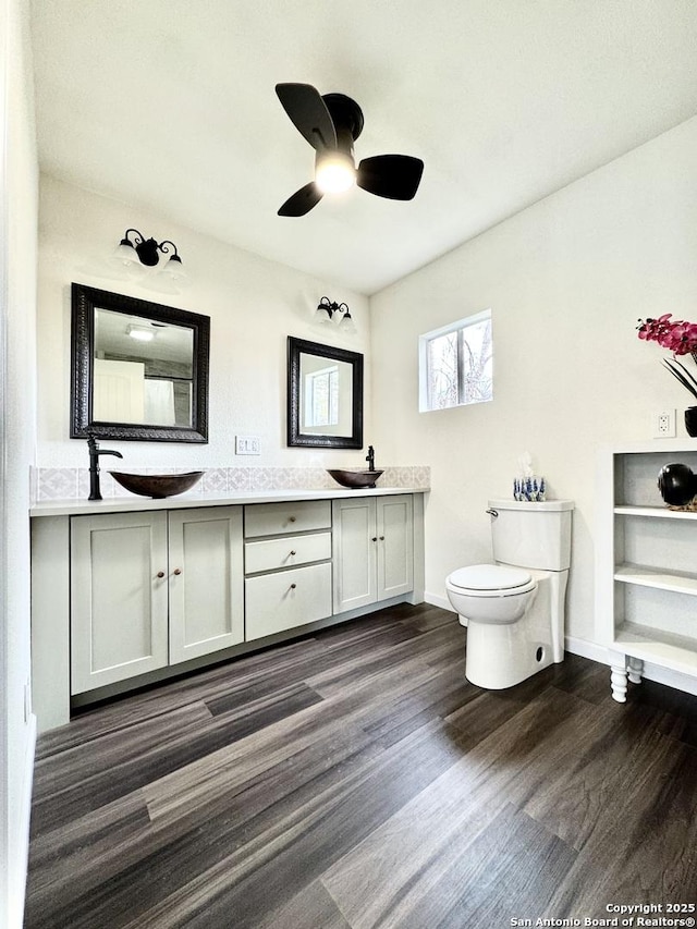 full bathroom featuring a sink, double vanity, toilet, and wood finished floors