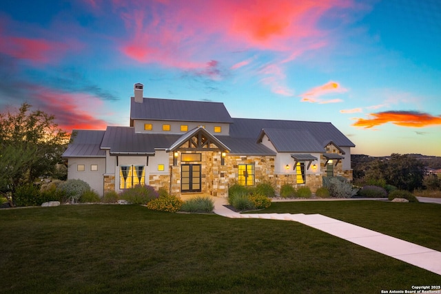 modern farmhouse featuring stone siding, metal roof, and a front yard