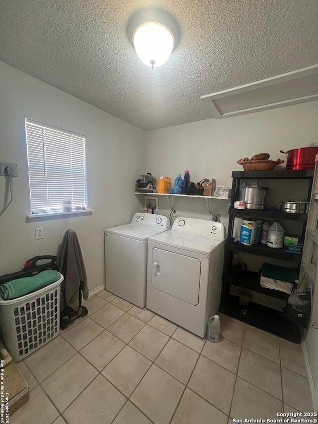 washroom with laundry area, light tile patterned floors, baseboards, washer and dryer, and a textured ceiling