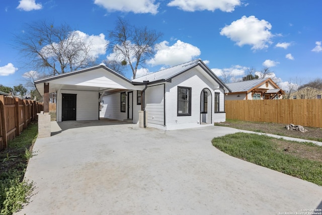 view of front facade with driveway, fence, a carport, and brick siding