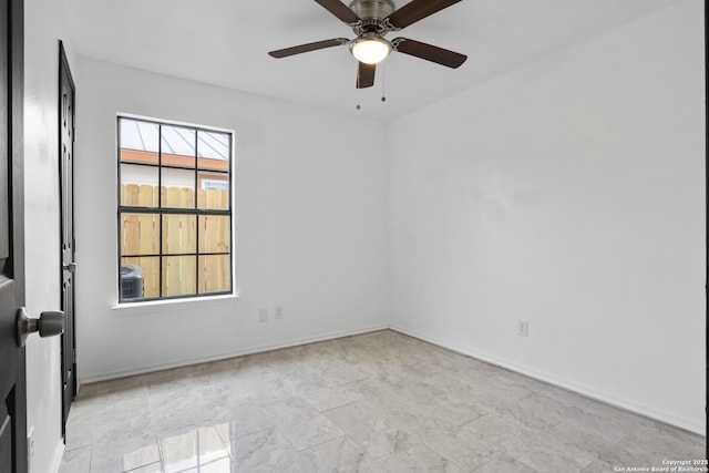 empty room with a ceiling fan and baseboards