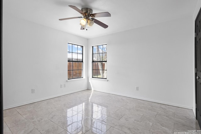 spare room featuring a ceiling fan and baseboards