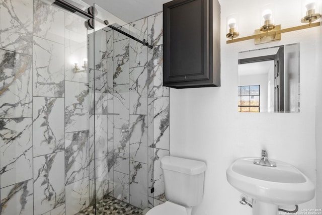 bathroom featuring toilet, a marble finish shower, and a sink
