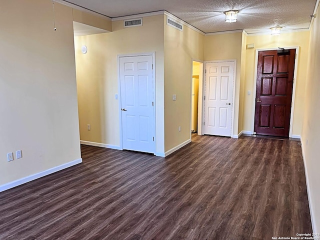 unfurnished room with ornamental molding, dark wood-style flooring, visible vents, and a textured ceiling