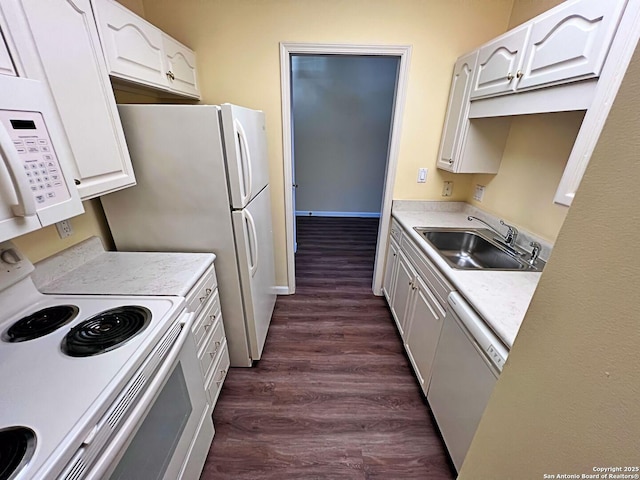 kitchen featuring white appliances, dark wood finished floors, light countertops, and a sink