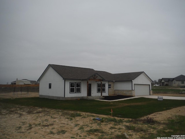 view of front facade featuring an attached garage, concrete driveway, and a front yard