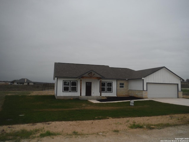 view of front of home featuring a front lawn, an attached garage, driveway, and a shingled roof